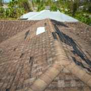 An image depicting the extent of roof damage due to weather with missing shingles and debris