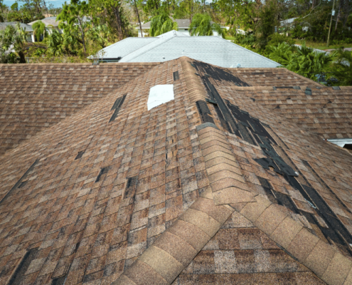 An image depicting the extent of roof damage due to weather with missing shingles and debris