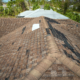 An image depicting the extent of roof damage due to weather with missing shingles and debris