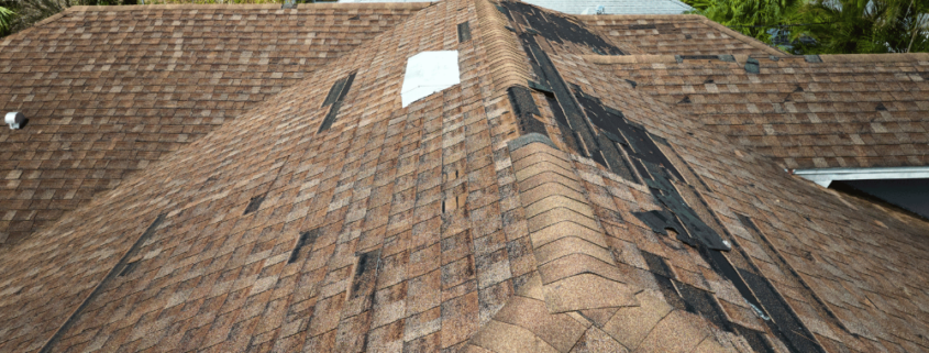 An image depicting the extent of roof damage due to weather with missing shingles and debris