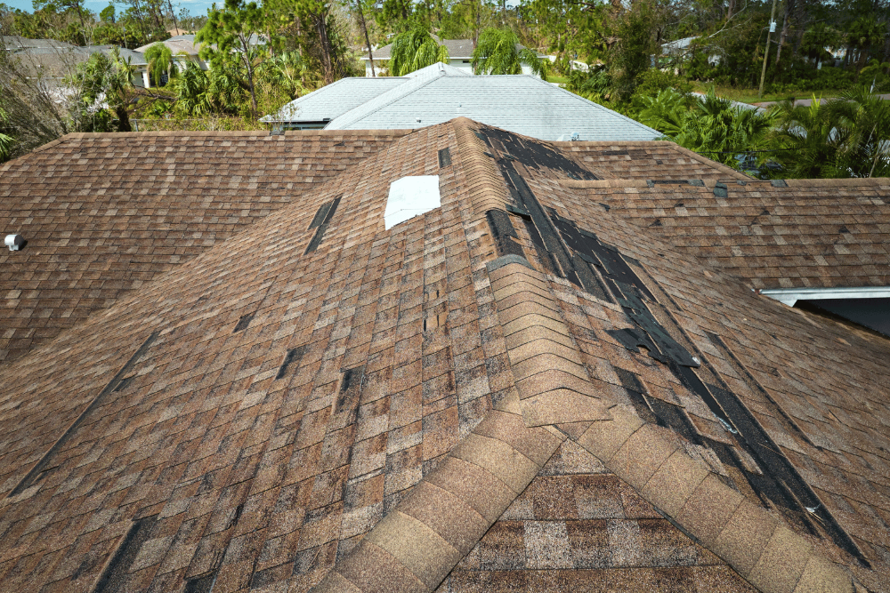 An image depicting the extent of roof damage due to weather with missing shingles and debris