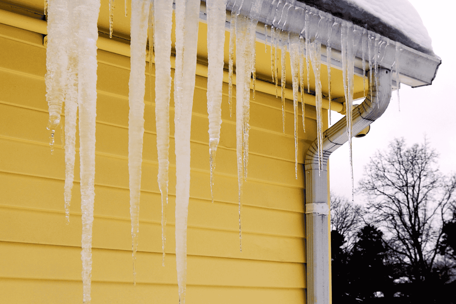 Clogged gutters filled with snow and icicles, indicating potential ice dam formation. Clogged gutters filled with snow and icicles, indicating potential ice dam formation.
