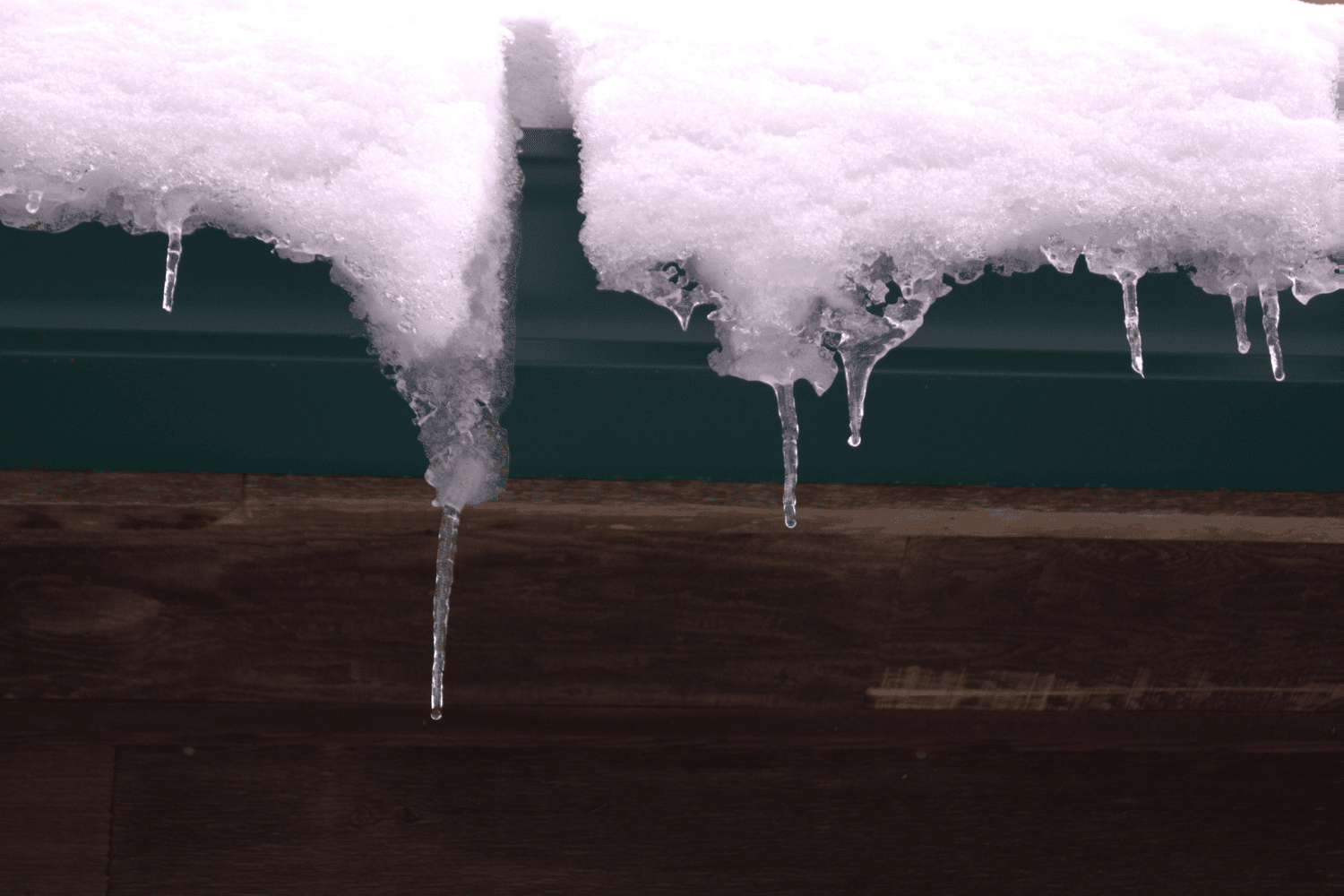 Damage caused by ice dams, with icicles visible on a roof. Damage caused by ice dams, with icicles visible on a roof.