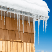 An illustration showing the formation of ice dams on a roof due to melting snow and freezing temperatures.
