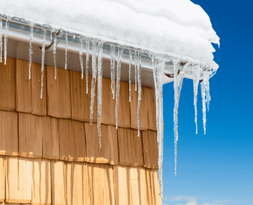 An illustration showing the formation of ice dams on a roof due to melting snow and freezing temperatures.